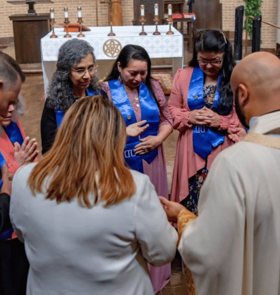 Father Elmer Herrera-Guzman, pastor of Holy Cross Catholic Church, prays with the graduating group of Holy Cross 